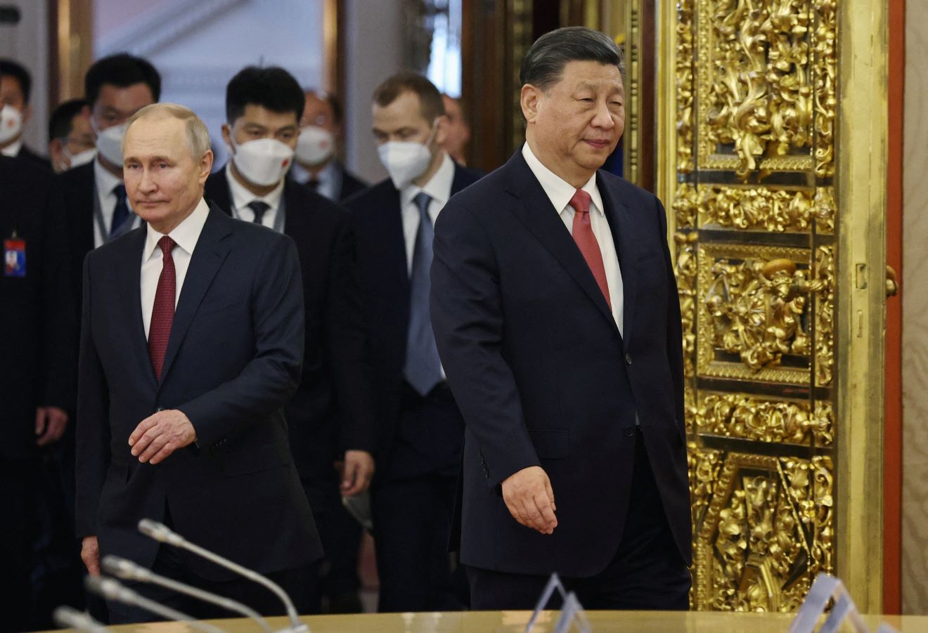 Russian President Vladimir Putin turns to his right and Chinese President Xi Jinping turns to his left as they enter a room with a golden door before talks at the Kremlin in Moscow, Russia on March 21, 2023. Sputnik/Mikhail Tereshchenko/Pool via REUTERS