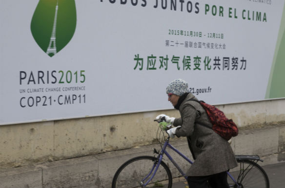 A cyclist pushes her bicycle in front of posters for the forthcoming COP 21 World Climate Summit in Paris, France, on November 2, 2015 (Philippe Wojazer/Reuters).