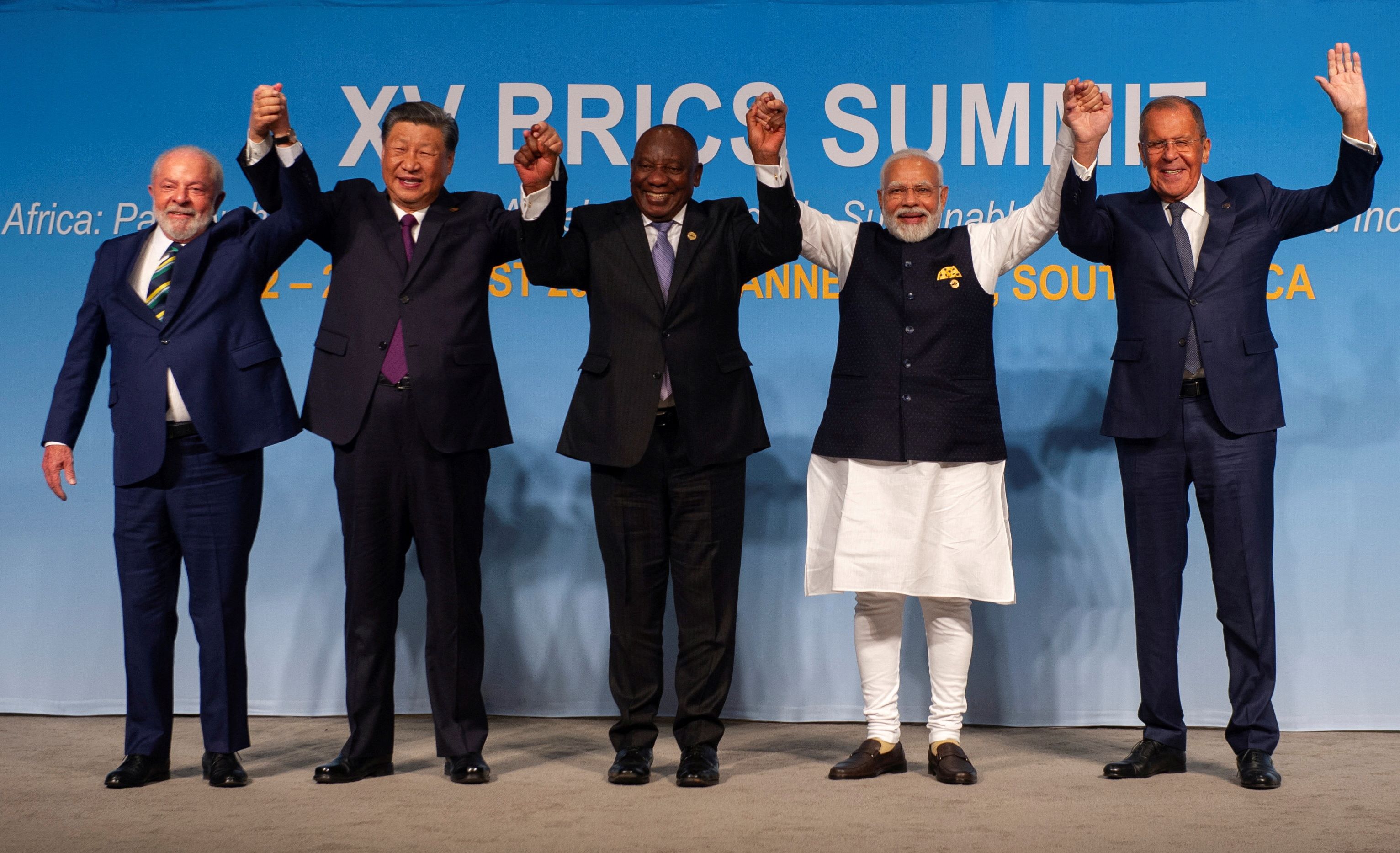 Brazil's President Luiz Inacio Lula da Silva, China's President Xi Jinping, South African President Cyril Ramaphosa, Indian Prime Minister Narendra Modi and Russia's Foreign Minister Sergei Lavrov pose for a picture standing up holding hands above their heads at the BRICS Summit in Johannesburg, South Africa on August 23, 2023. 