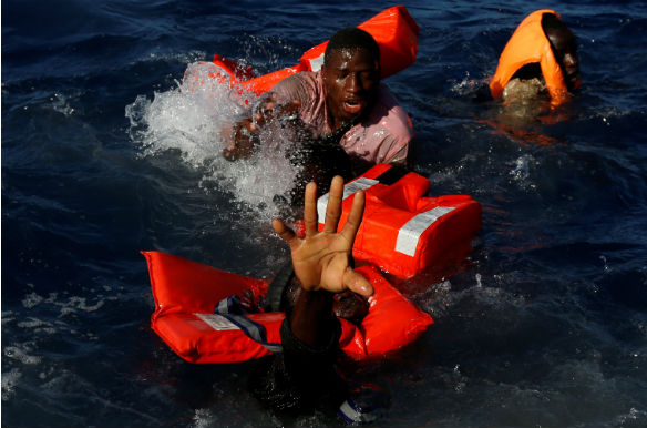 Migrants try to stay afloat after falling off their rubber dinghy during a rescue operation in the central Mediterranean some fifteen nautical miles off the Libyan coast on April 14, 2017 (DARRIN ZAMMIT LUPI/REUTERS).
