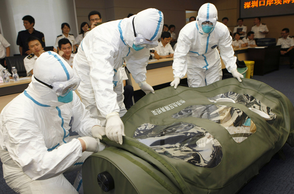 Health inspection officers help a mock patient into a negative pressure isolation stretcher, during a drill to demonstrate the procedures of transporting an Ebola victim, at Shenzhen Entry-exit Inspection and Quarantine Bureau (Stringer/Courtesy Reuters)